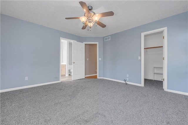 unfurnished bedroom featuring a spacious closet, carpet flooring, baseboards, and visible vents