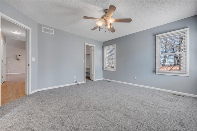 unfurnished bedroom featuring visible vents, multiple windows, and carpet floors