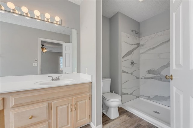 full bath with a shower stall, toilet, vanity, wood finished floors, and a textured ceiling