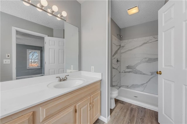 bathroom featuring a marble finish shower, toilet, vanity, and a textured ceiling