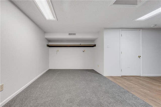 basement with visible vents, a textured ceiling, and wood finished floors