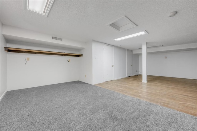 finished basement with visible vents, a textured ceiling, and carpet