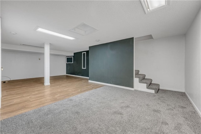 finished below grade area featuring wood finished floors, baseboards, stairs, a textured ceiling, and carpet flooring