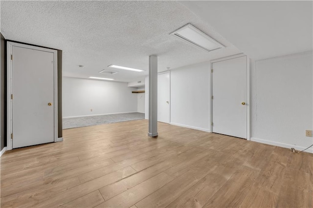 finished below grade area featuring baseboards, a textured ceiling, and light wood-style floors