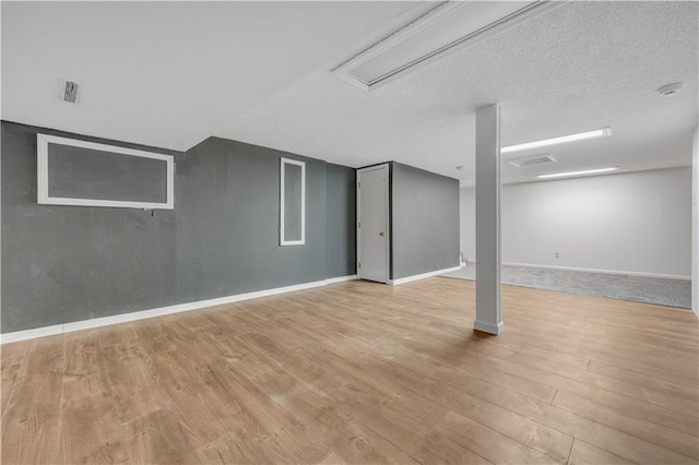 basement featuring a textured ceiling, baseboards, and wood finished floors