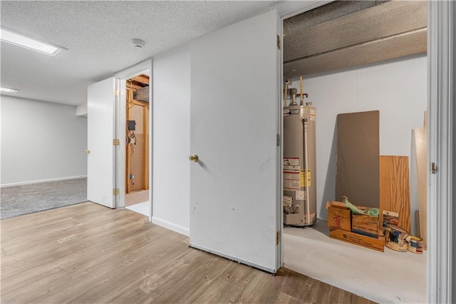 finished basement featuring water heater, a textured ceiling, baseboards, and wood finished floors