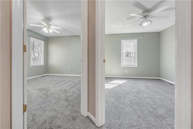 unfurnished room featuring carpet flooring, a textured ceiling, baseboards, and ceiling fan