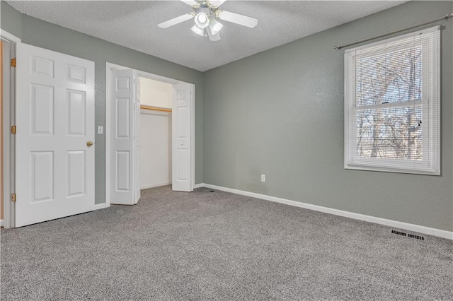 unfurnished bedroom featuring carpet flooring, baseboards, visible vents, and a textured ceiling