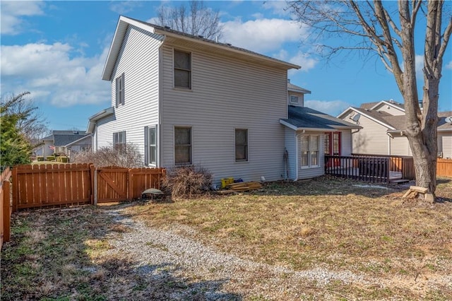 rear view of house featuring a gate, a wooden deck, a lawn, and fence