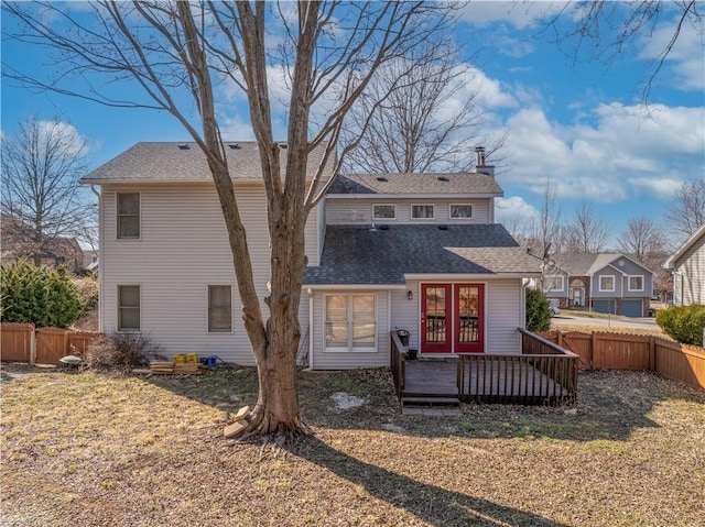 rear view of property featuring a fenced backyard, a chimney, roof with shingles, and a wooden deck