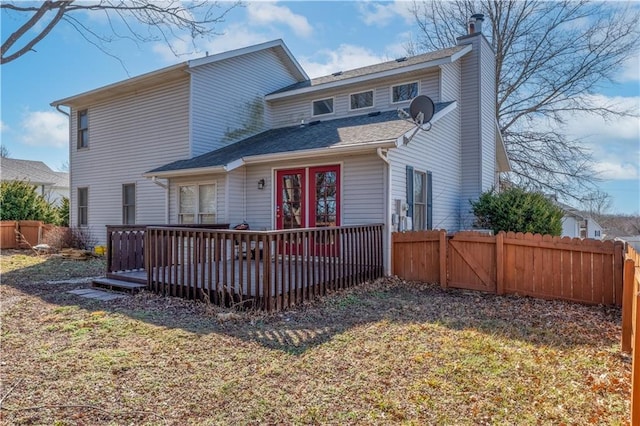 view of front of house featuring a wooden deck, fence, a front lawn, and a chimney