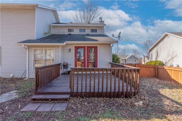 exterior space with a shingled roof, fence, a chimney, and a wooden deck