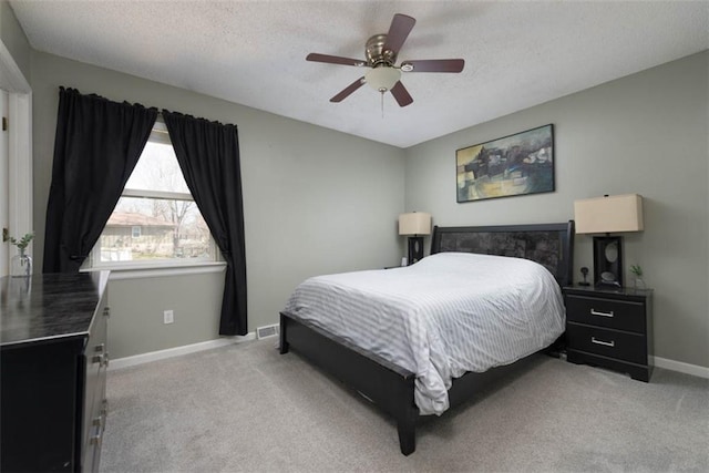 bedroom featuring a textured ceiling, ceiling fan, baseboards, and light carpet