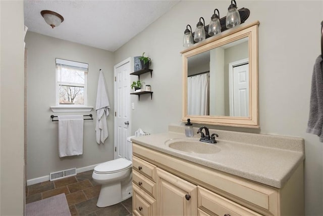 bathroom featuring vanity, toilet, baseboards, and visible vents