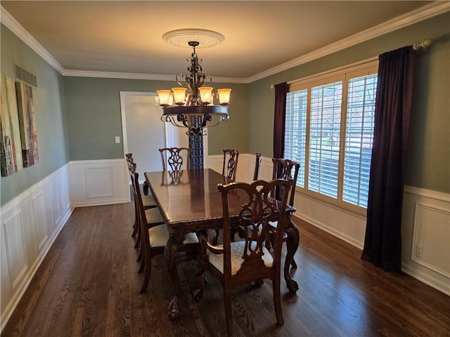 dining room featuring visible vents, dark wood-type flooring, ornamental molding, wainscoting, and an inviting chandelier