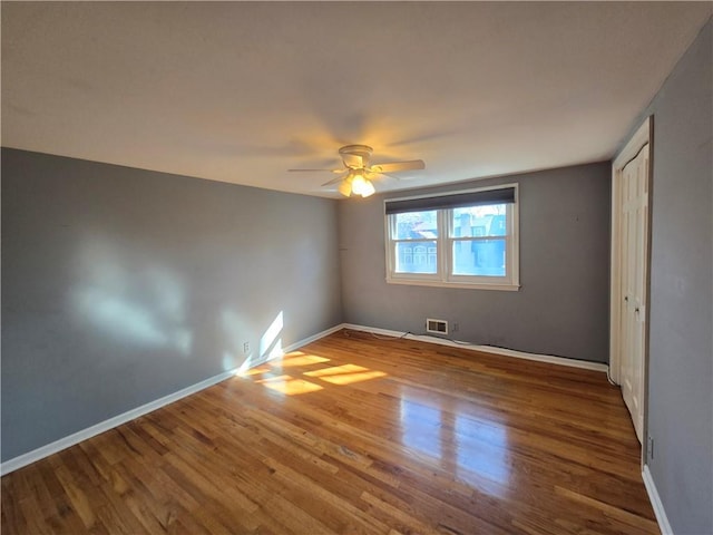 unfurnished bedroom featuring visible vents, baseboards, wood finished floors, and a ceiling fan