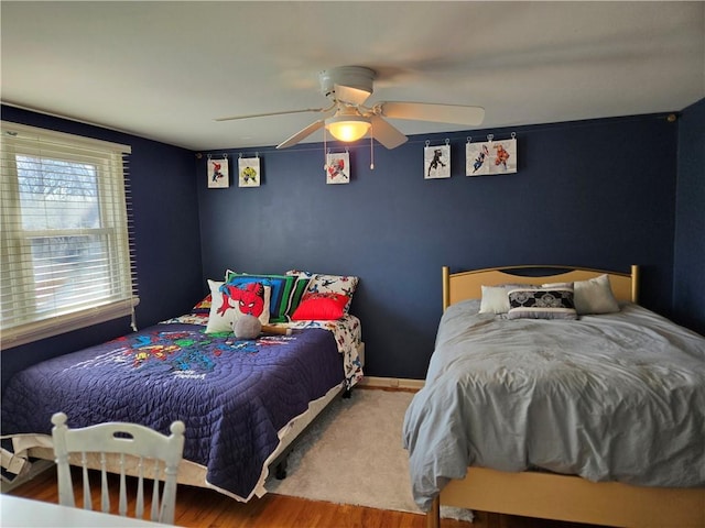 bedroom with a ceiling fan, wood finished floors, and baseboards