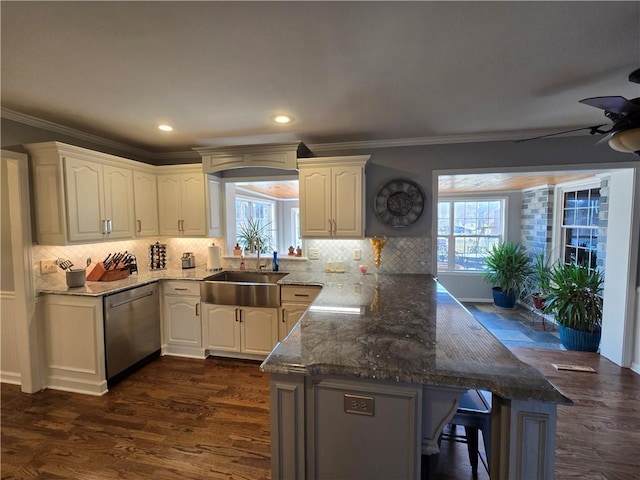 kitchen featuring a sink, ceiling fan, a peninsula, a kitchen breakfast bar, and stainless steel dishwasher