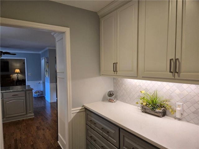 kitchen featuring ornamental molding, gray cabinets, dark wood-style floors, wainscoting, and light countertops