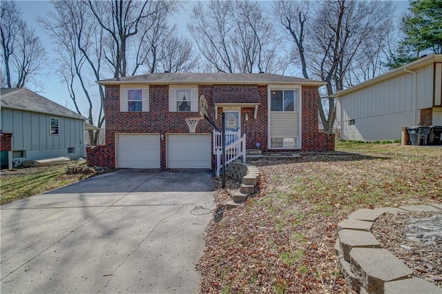 raised ranch with brick siding, an attached garage, and driveway