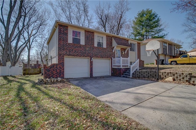 raised ranch featuring driveway, a gate, fence, a garage, and brick siding