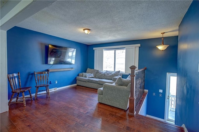 living room featuring wood finished floors, baseboards, and a textured ceiling