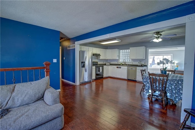 living room featuring dark wood finished floors, ceiling fan, visible vents, and a textured ceiling