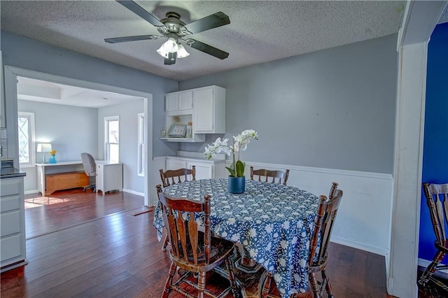 dining space with dark wood-type flooring, a ceiling fan, baseboards, and a textured ceiling