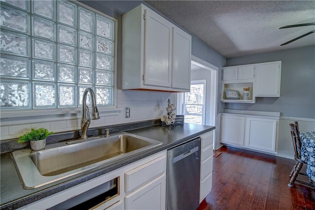 kitchen with dark countertops, a sink, white cabinetry, and stainless steel dishwasher