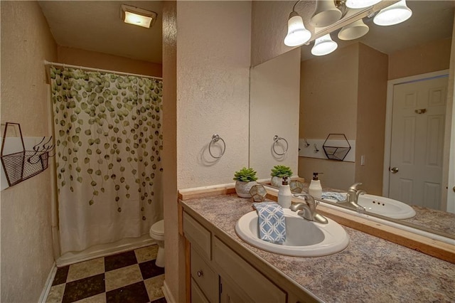 bathroom with tile patterned floors, toilet, vanity, and a textured wall