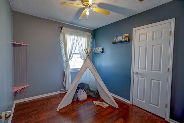 game room with baseboards, a textured ceiling, hardwood / wood-style floors, and a ceiling fan