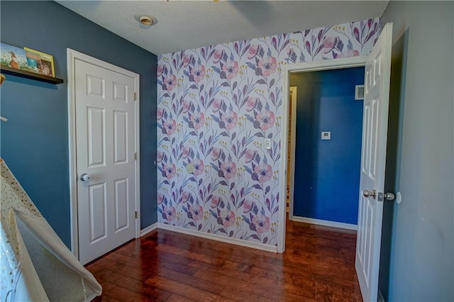 bedroom featuring a textured ceiling, wallpapered walls, baseboards, and hardwood / wood-style flooring