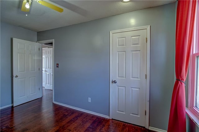 unfurnished bedroom featuring a ceiling fan, dark wood-style floors, and baseboards