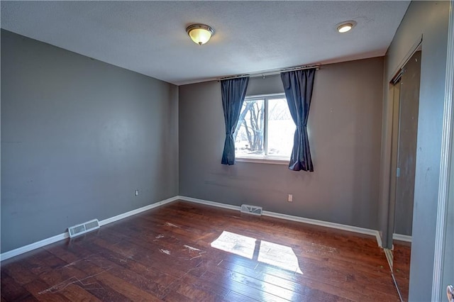 unfurnished bedroom with visible vents, wood-type flooring, a textured ceiling, and baseboards