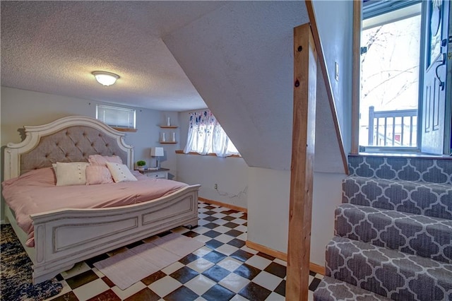 bedroom featuring light floors, baseboards, and a textured ceiling