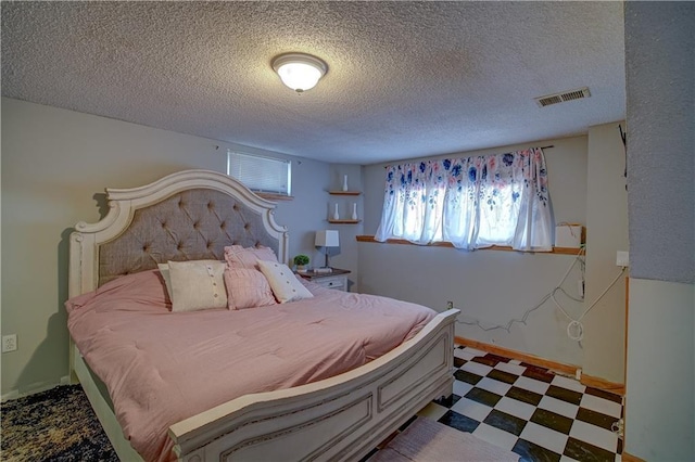 bedroom with tile patterned floors, baseboards, visible vents, and a textured ceiling