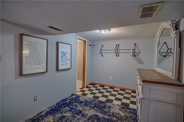 interior space featuring tile patterned floors, baseboards, visible vents, and a textured ceiling