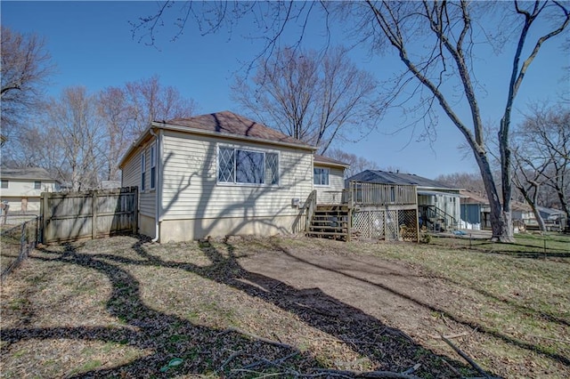 view of side of home featuring stairs, a deck, and fence