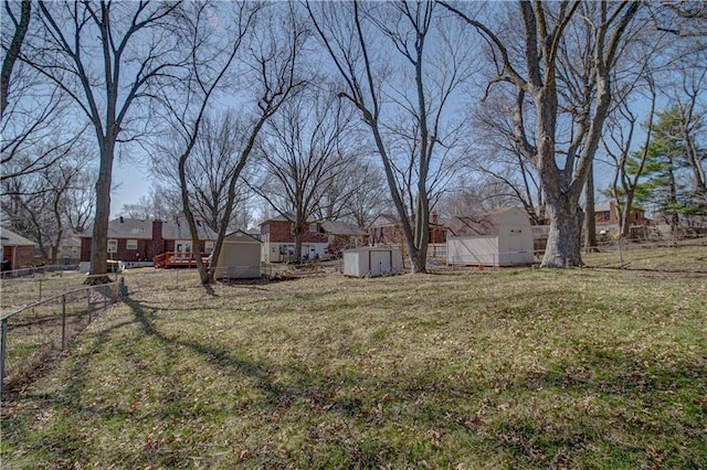 view of yard with a residential view, an outbuilding, a storage shed, and fence