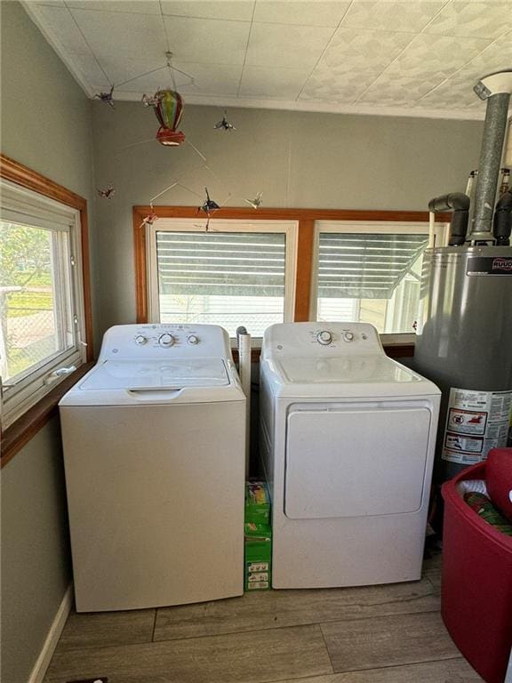 washroom featuring gas water heater, wood finished floors, washing machine and dryer, and laundry area