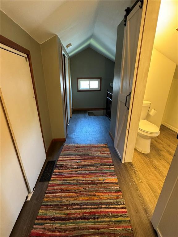 hallway with lofted ceiling and dark wood-type flooring