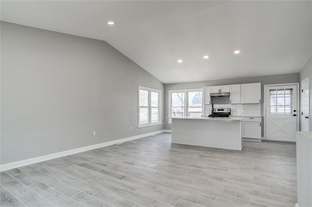 kitchen featuring electric range, vaulted ceiling, light wood-style floors, under cabinet range hood, and white cabinetry