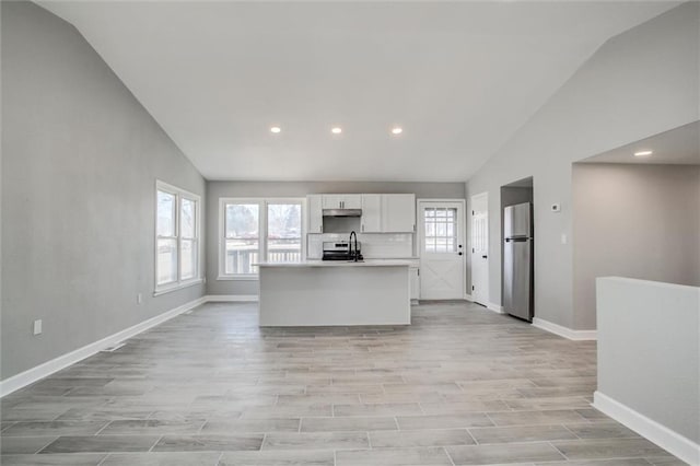 kitchen featuring a kitchen island with sink, stainless steel appliances, light countertops, white cabinets, and light wood-style floors