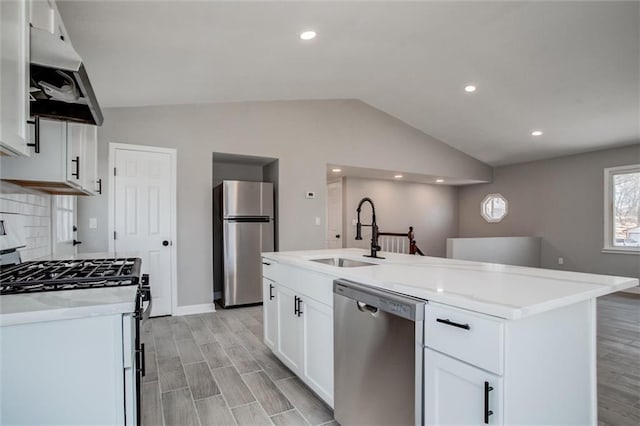 kitchen featuring a sink, under cabinet range hood, stainless steel appliances, light wood-style floors, and lofted ceiling