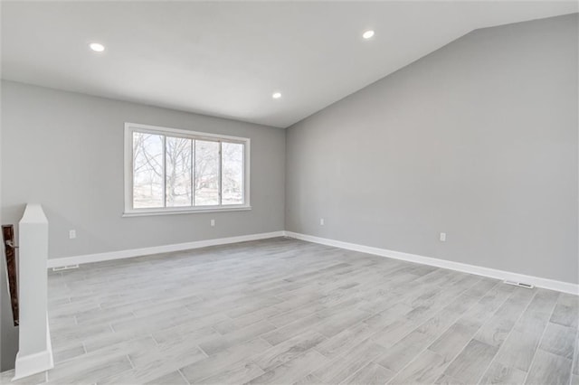 empty room featuring vaulted ceiling, recessed lighting, baseboards, and light wood finished floors