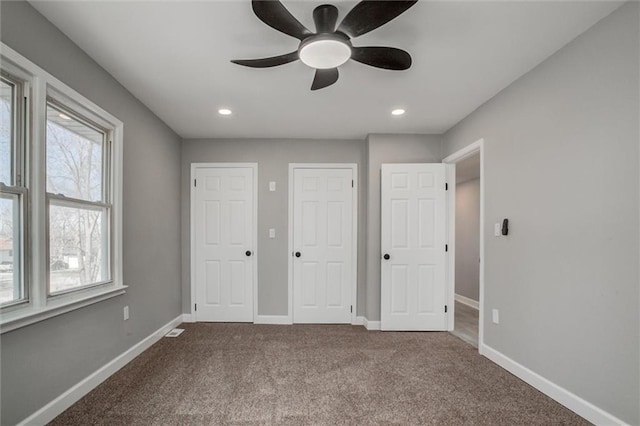 unfurnished bedroom with recessed lighting, baseboards, carpet, and multiple closets