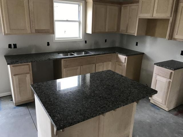 kitchen with a sink, stone countertops, unfinished concrete flooring, and a center island