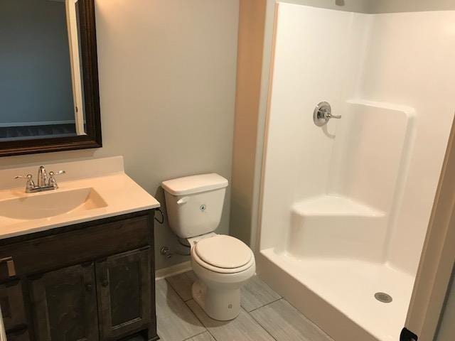 bathroom with toilet, a stall shower, and vanity