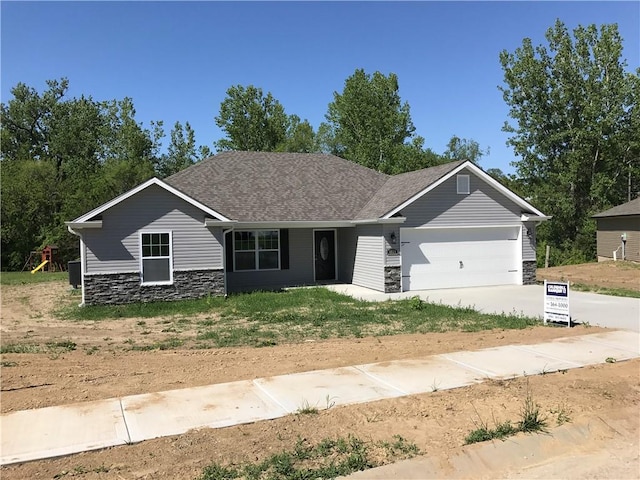 ranch-style house featuring concrete driveway, an attached garage, and stone siding