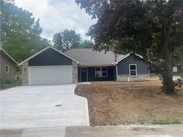 2101 N 31st Ter, Saint Joseph, MO 64506 - ranch-style home with stone siding, a garage, concrete driveway, and a shingled roof